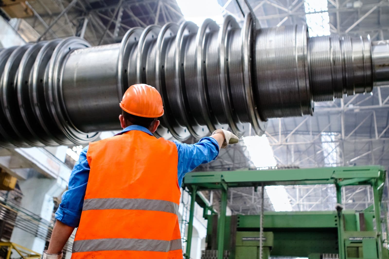 An engineer in high-visibility safety gear inspecting industrial equipment