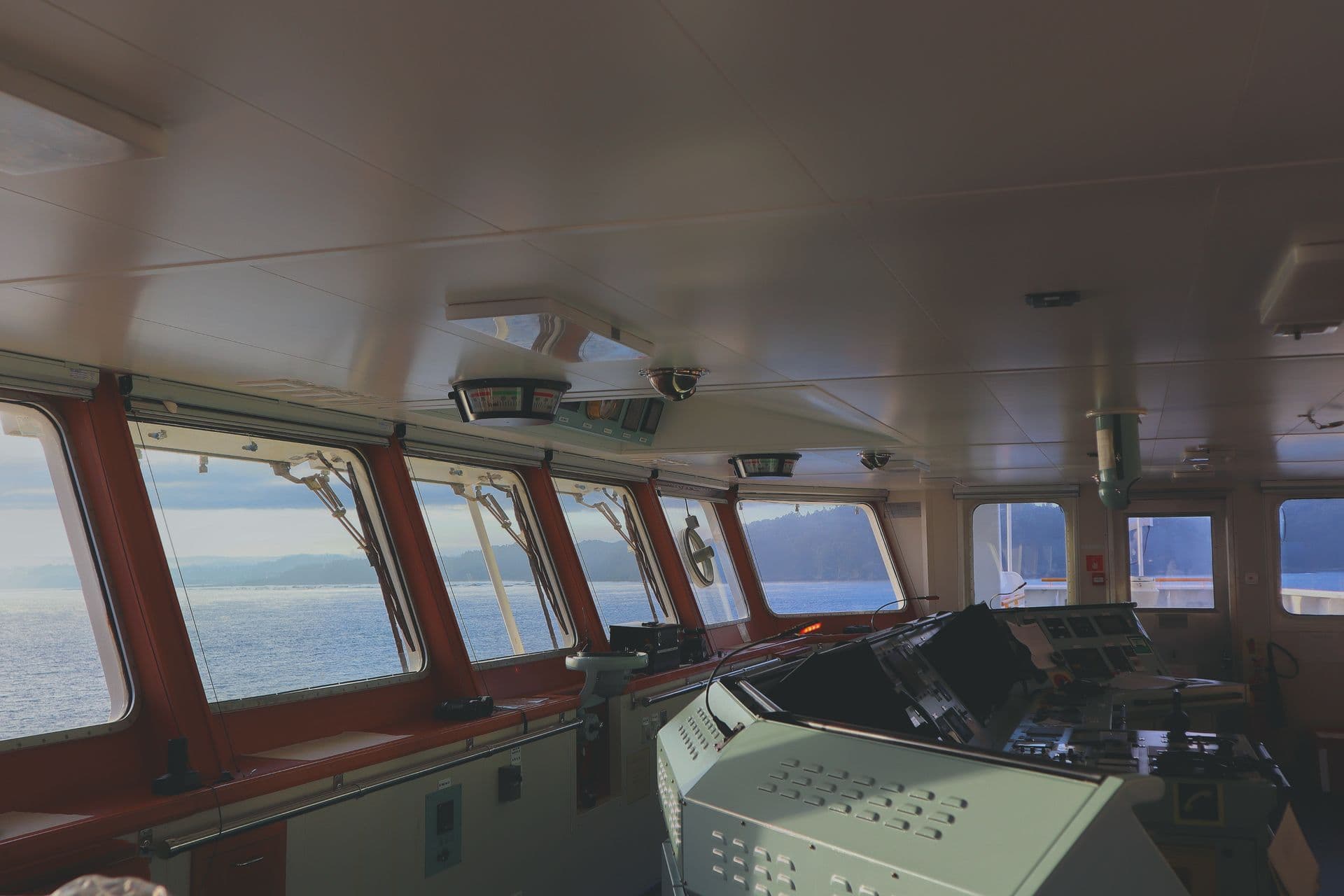 A ship's wheelhouse: forward bridge windows with a clear-view screen and wipers, and the bridge consoles