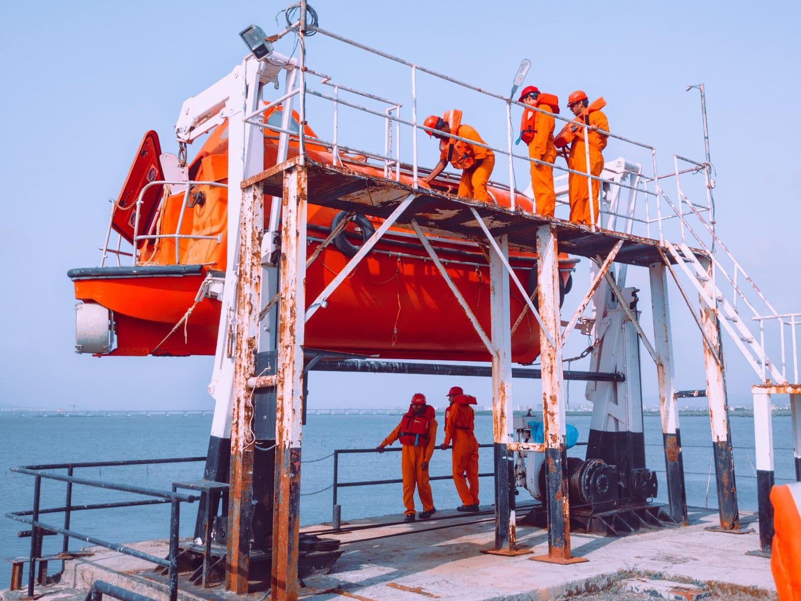 A ship's crew in safety gear conducting a lifeboat drill